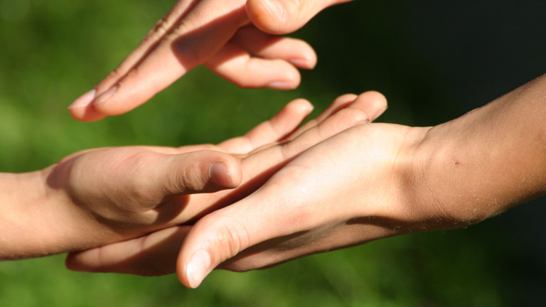 Eine menschliche Hand greift in eine andere und verdeutlicht den Wunsch nach Verständigung Eine menschliche Hand greift in eine andere und verdeutlicht den Wunsch nach Verständigung