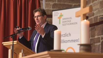 Pastor Thorsten Graff, Leiter des Konzernbereichs Seelsorge-Theologie-Ethik, spricht am Rednerpult auf der Bühne mit Kerzen und einem Holzkreuz beim Zusammenschluss von Diakonie Werratal und Immanuel Diakonie Südthüringen im Kressehof im Meininger Ortsteil Walldorf Pastor Thorsten Graff, Leiter des Konzernbereichs Seelsorge-Theologie-Ethik, spricht am Rednerpult auf der Bühne mit Kerzen und einem Holzkreuz beim Zusammenschluss von Diakonie Werratal und Immanuel Diakonie Südthüringen im Kressehof im Meininger Ortsteil Walldorf