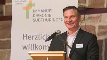Andreas Mende, Konzerngeschäftsführer der Immanuel Albertinen Diakonie, spricht am Pult mit einem Mikrofon beim Zusammenschluss von Diakonie Werratal und Immanuel Diakonie Südthüringen im Kressehof im Meininger Ortsteil Walldorf Andreas Mende, Konzerngeschäftsführer der Immanuel Albertinen Diakonie, spricht am Pult mit einem Mikrofon beim Zusammenschluss von Diakonie Werratal und Immanuel Diakonie Südthüringen im Kressehof im Meininger Ortsteil Walldorf
